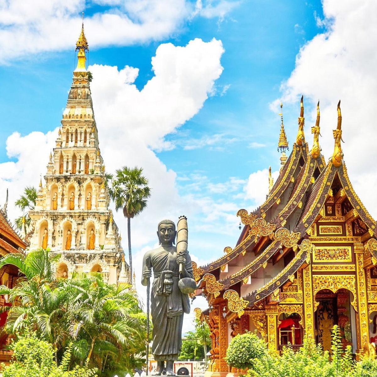 Golden temple spires and a Buddha statue in Thailand.